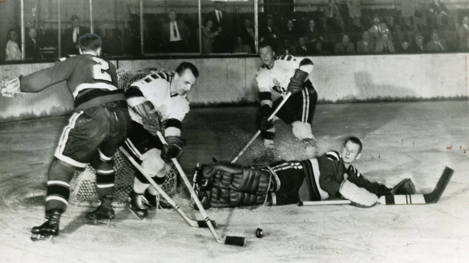 Buffalo's Pete Babando attacks the Providence Reds net against goalie Johnny Bower and defenseman Bill Folk during a 1956 Calder Cup playoff game in Providence. Historical file photo; the 2026 AHL preseason is not shown.