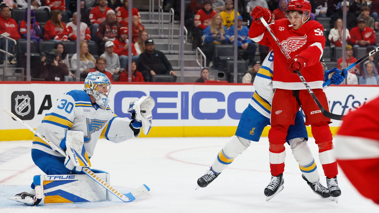 St. Louis Blues goaltender Joel Hofer makes a save as Detroit Red Wings forward Emmitt Finnie jumps in front of the net.