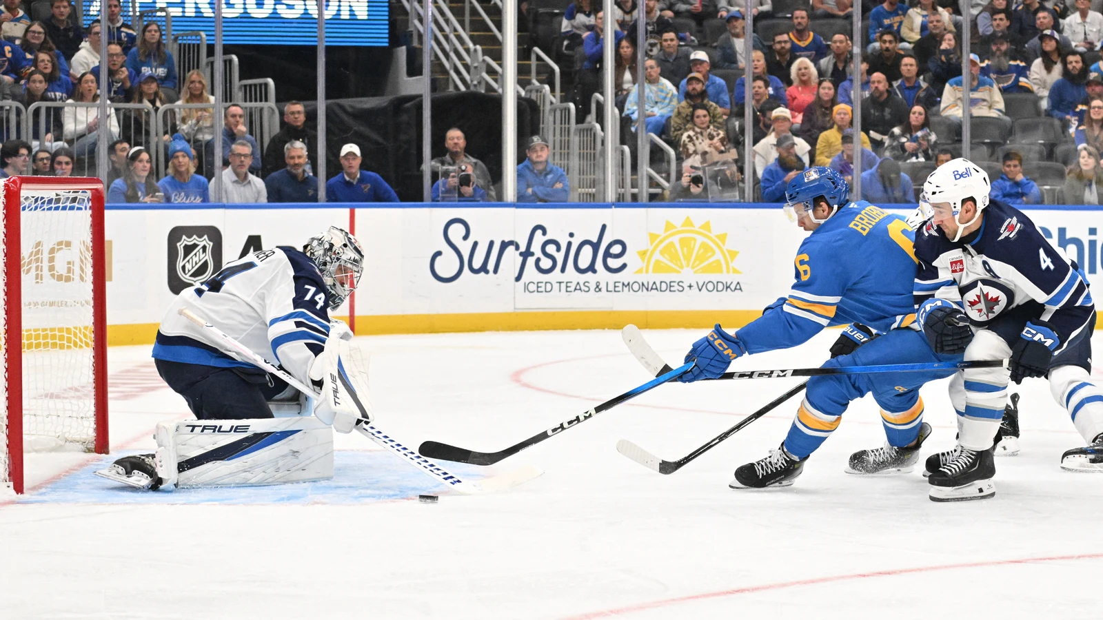 St. Louis Blues defenceman Philip Broberg plays the puck near Winnipeg Jets goaltender Stuart Skinner and defenceman Neal Pionk.