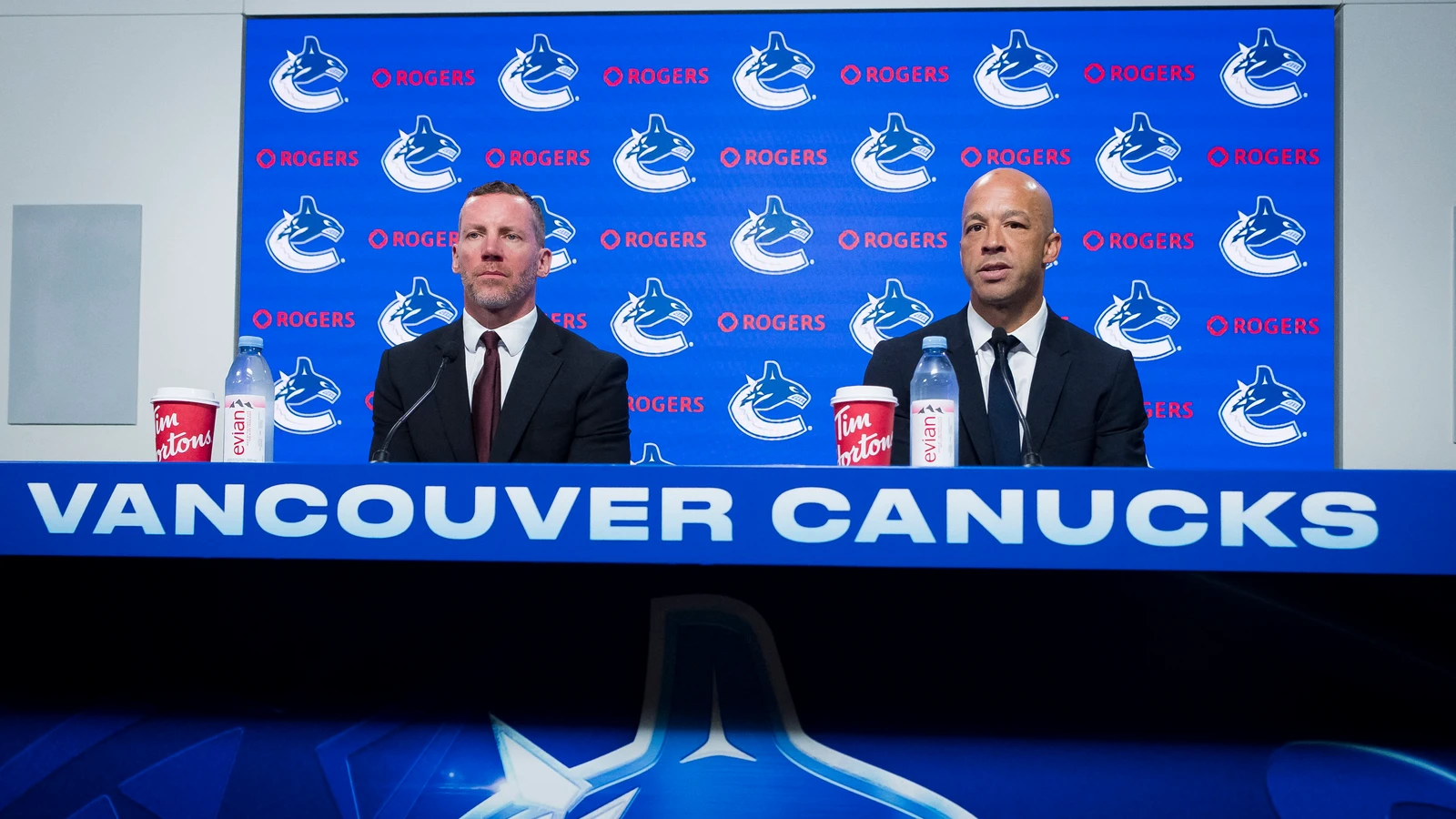 Canucks general manager Ryan Johnson, left, listens as Manny Malhotra speaks at Vancouver’s June 4, 2026 coaching press conference. File photo; Ryan Stewart is not pictured.