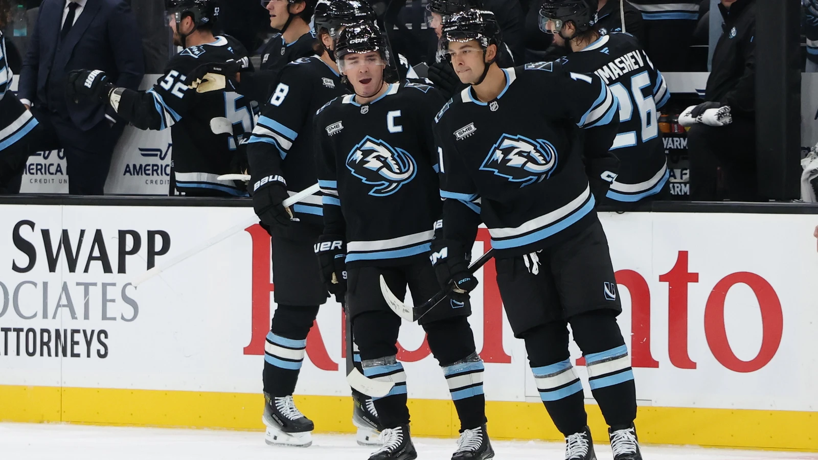 Dylan Guenther and Clayton Keller celebrate a Utah Mammoth goal beside the bench against the Chicago Blackhawks.