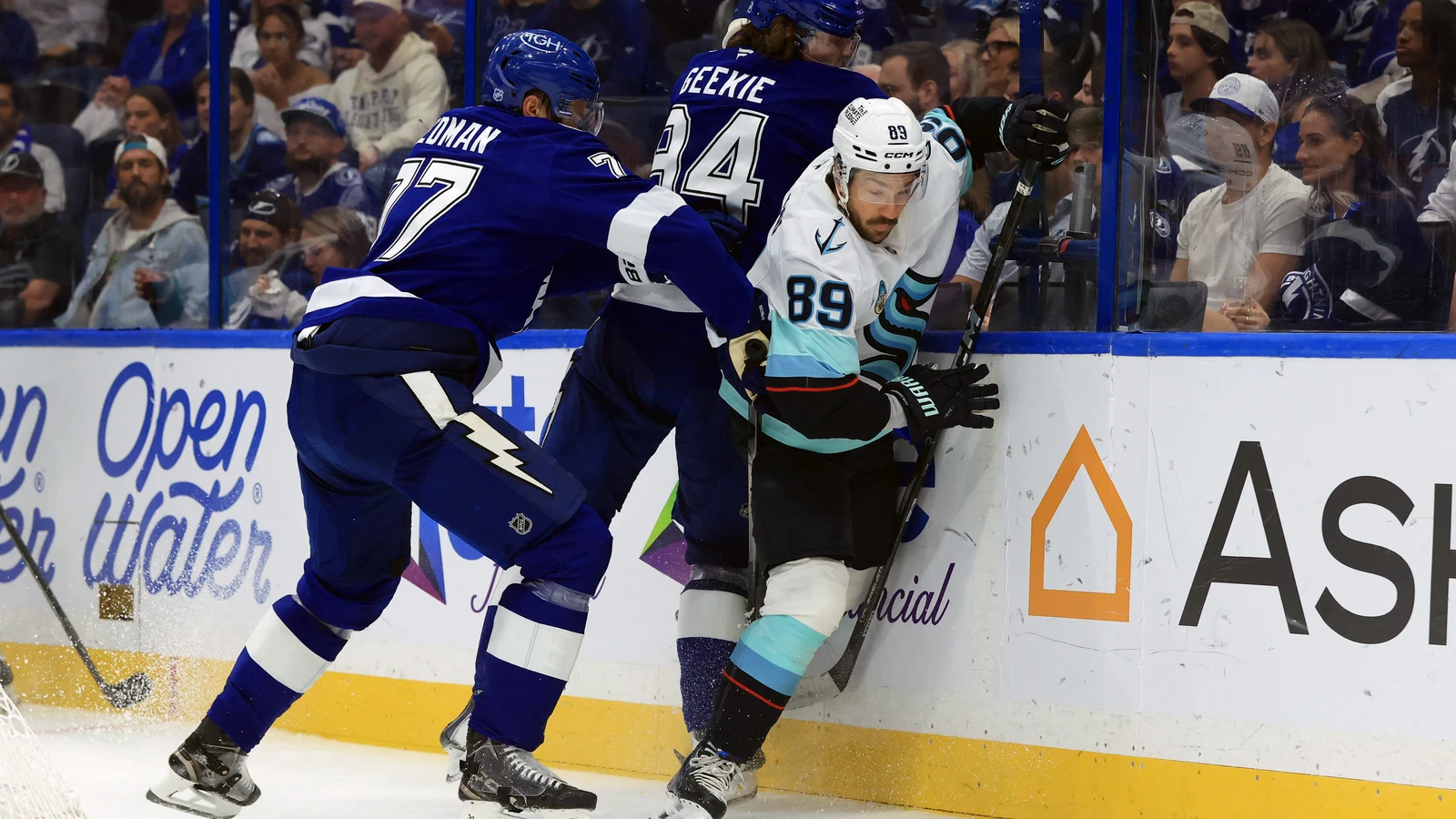 Tampa Bay Lightning defenceman Victor Hedman and centre Conor Geekie battle Seattle Kraken centre Frederick Gaudreau along the boards at Benchmark International Arena.