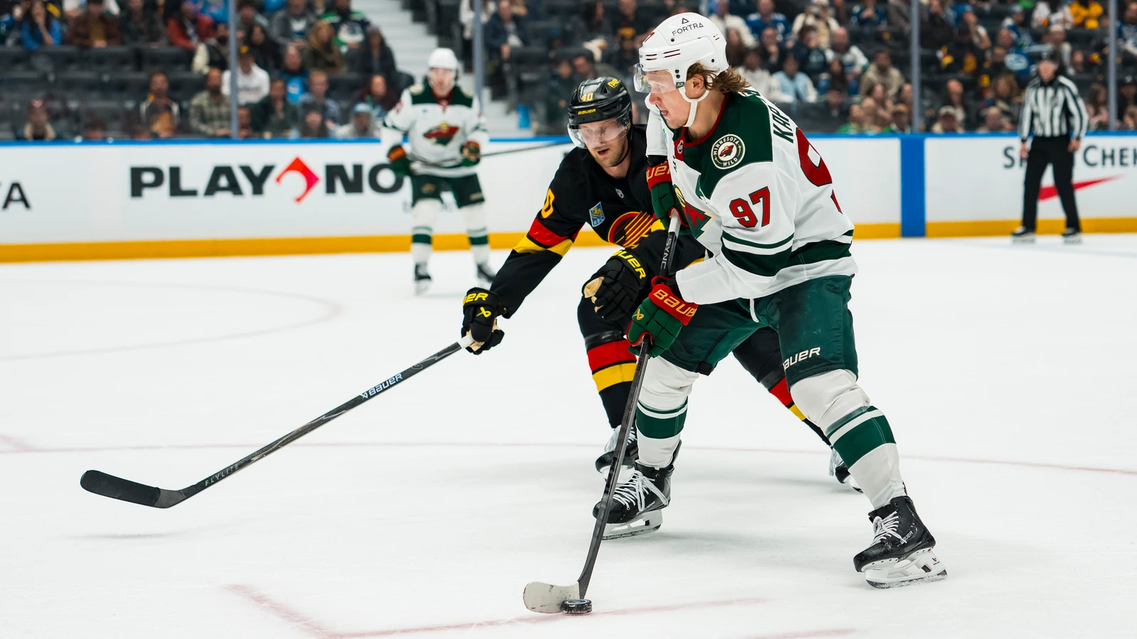 File photo: Minnesota Wild forward Kirill Kaprizov carries the puck past Vancouver Canucks forward Elias Pettersson.