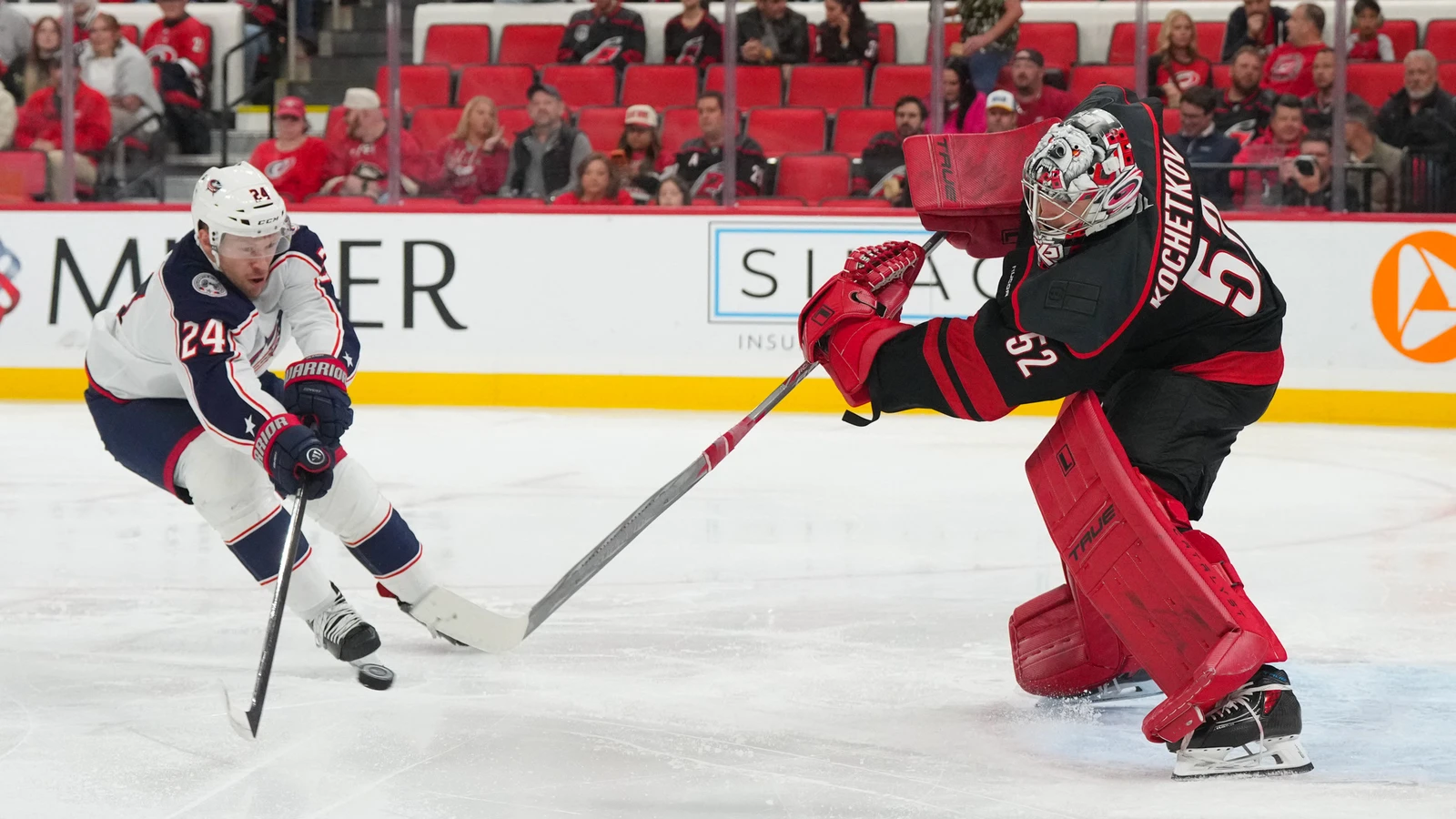 Carolina Hurricanes goaltender Pyotr Kochetkov clears the puck as Columbus Blue Jackets forward Mathieu Olivier approaches at Lenovo Center.