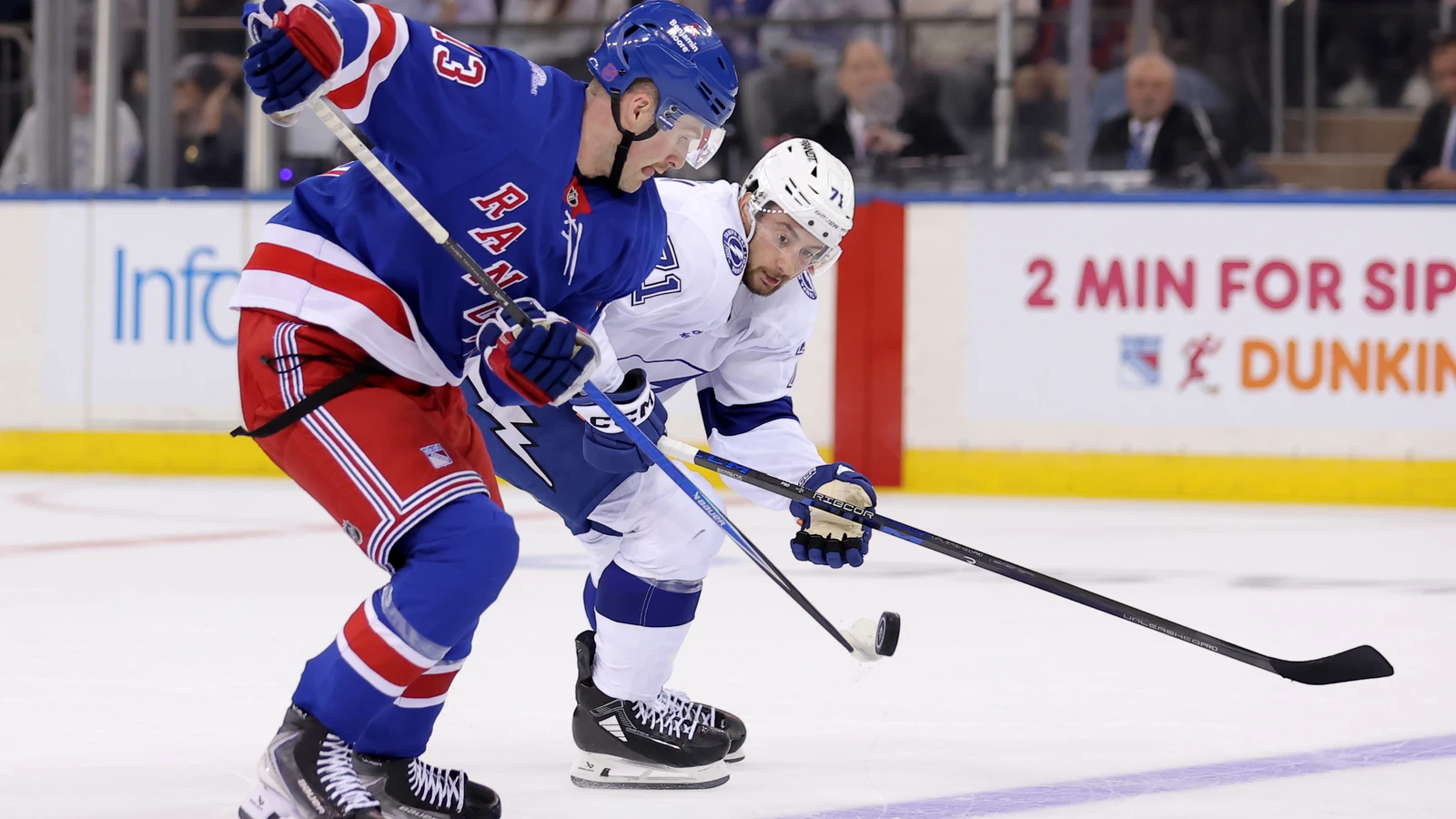 New York Rangers winger Alexis Lafrenière plays the puck as a Tampa Bay Lightning skater challenges him at Madison Square Garden.