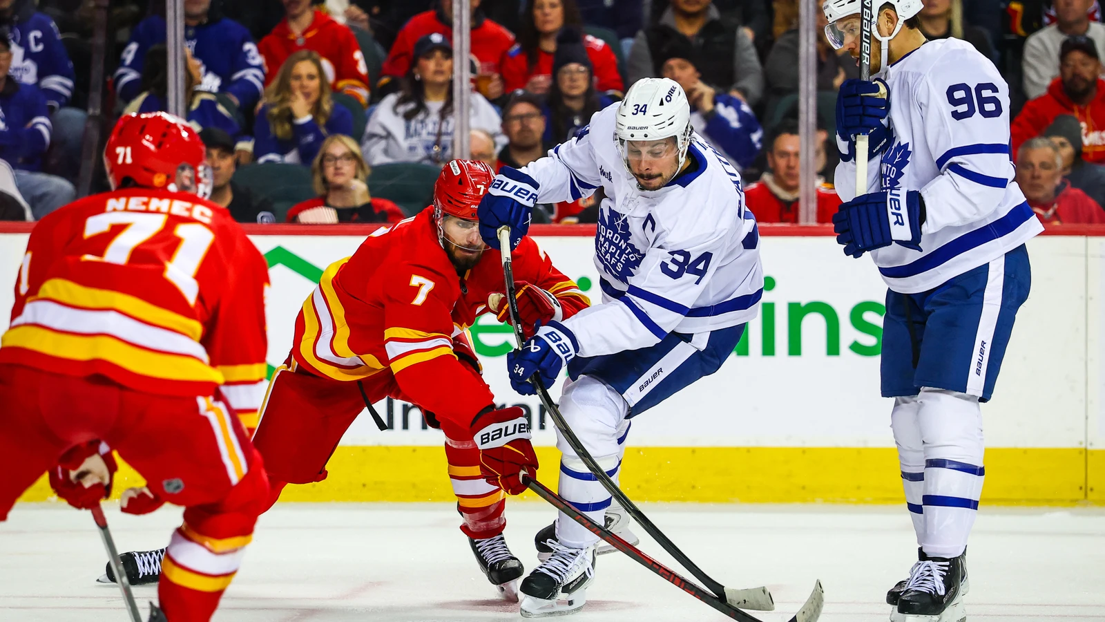 Auston Matthews battles for the puck against the Calgary Flames at Scotiabank Saddledome.