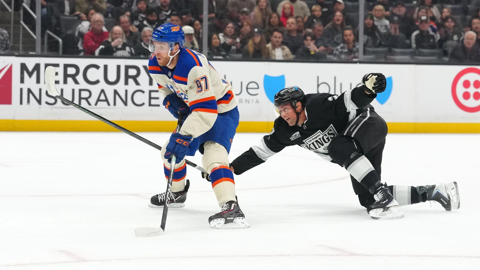 Connor McDavid skates with the puck as a Los Angeles Kings defenceman falls behind him at Crypto.com Arena.