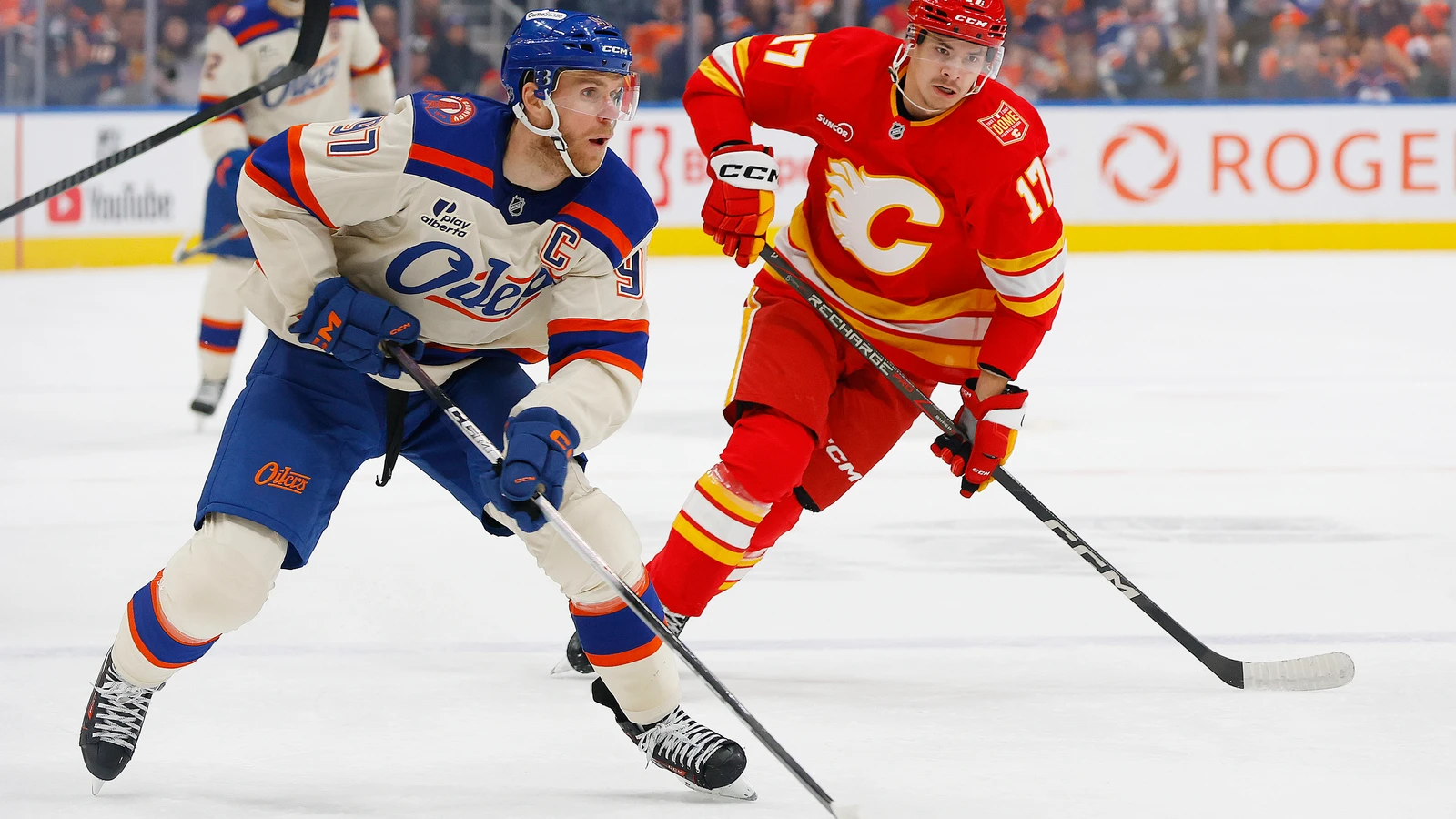 Edmonton Oilers captain Connor McDavid skates with the puck in front of Calgary Flames forward Yegor Sharangovich at Rogers Place.