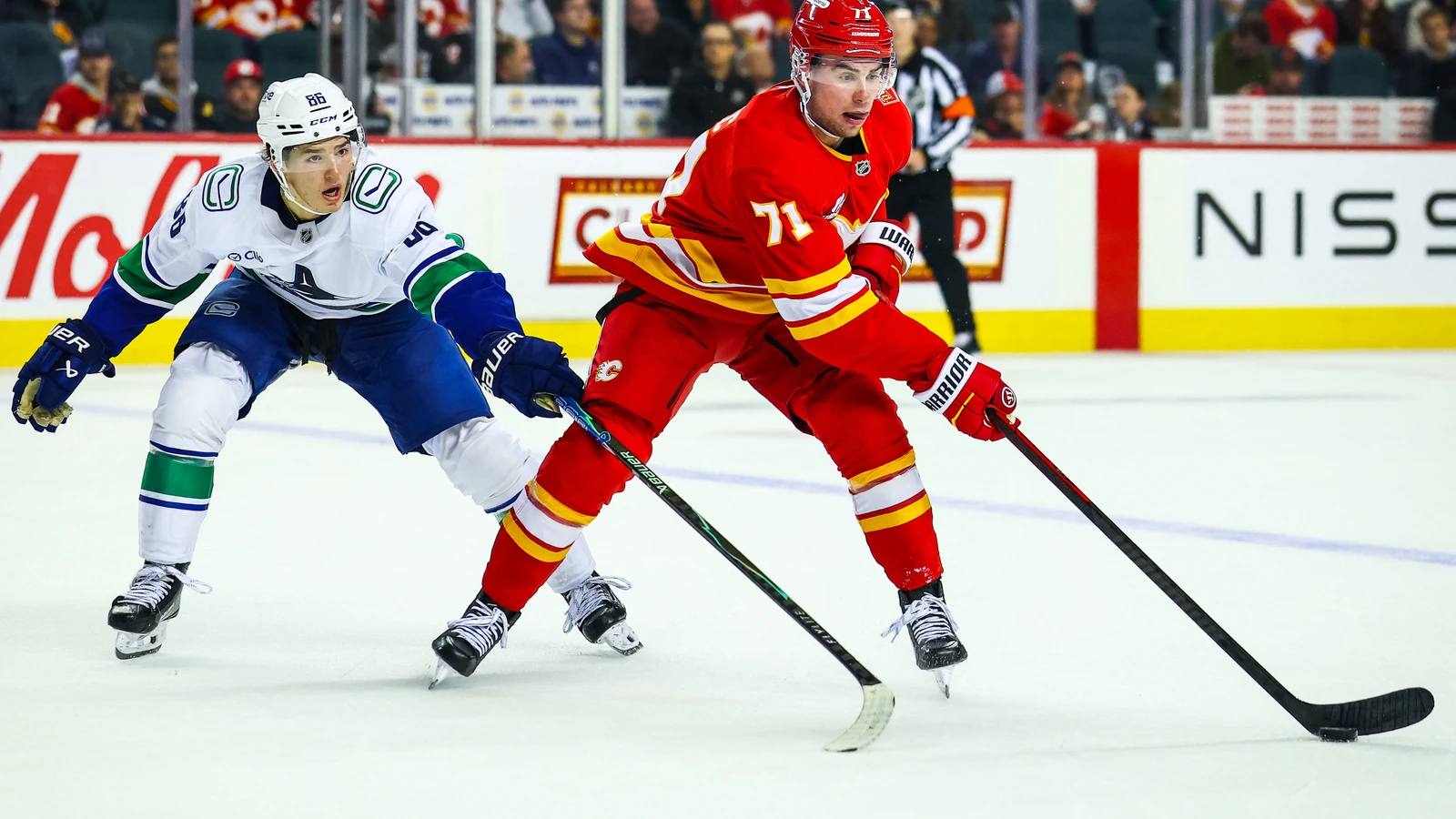Calgary Flames defenseman Simon Nemec (71) controls the puck against Vancouver Canucks center Braeden Cootes (86) at Scotiabank Saddledome on Sept. 22, 2026.