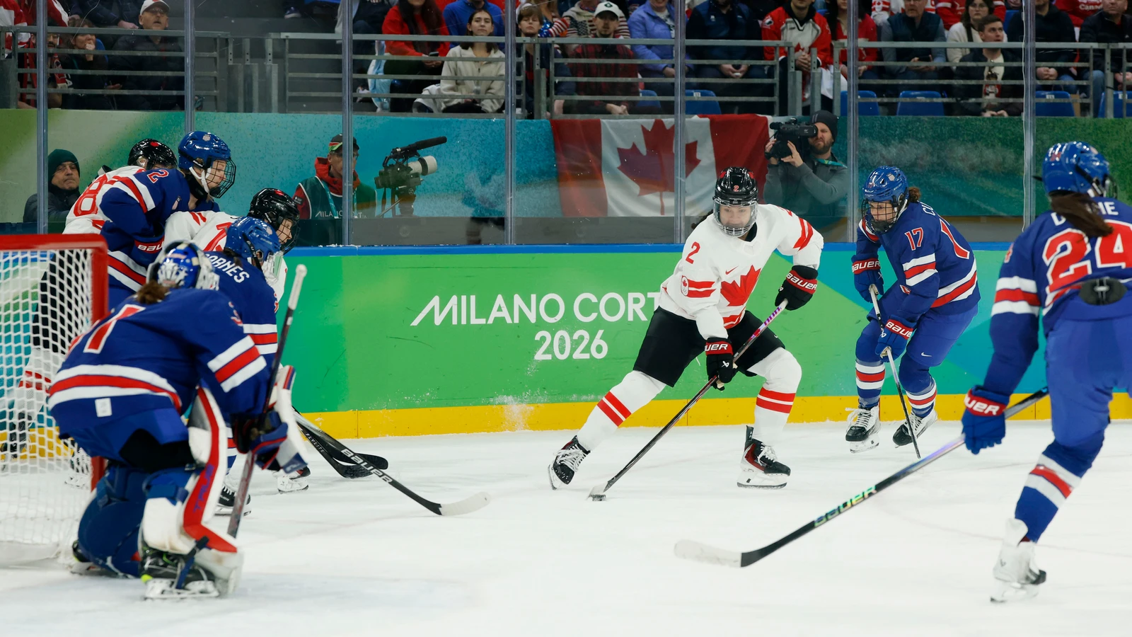 Canada defender Sophie Jaques carries the puck as United States forward Britta Curl defends during the 2026 Olympic women's hockey gold-medal game in Milan. File photo; this shows Olympic game action, not Traverse City, the PWHL summer camp or youth instruction.