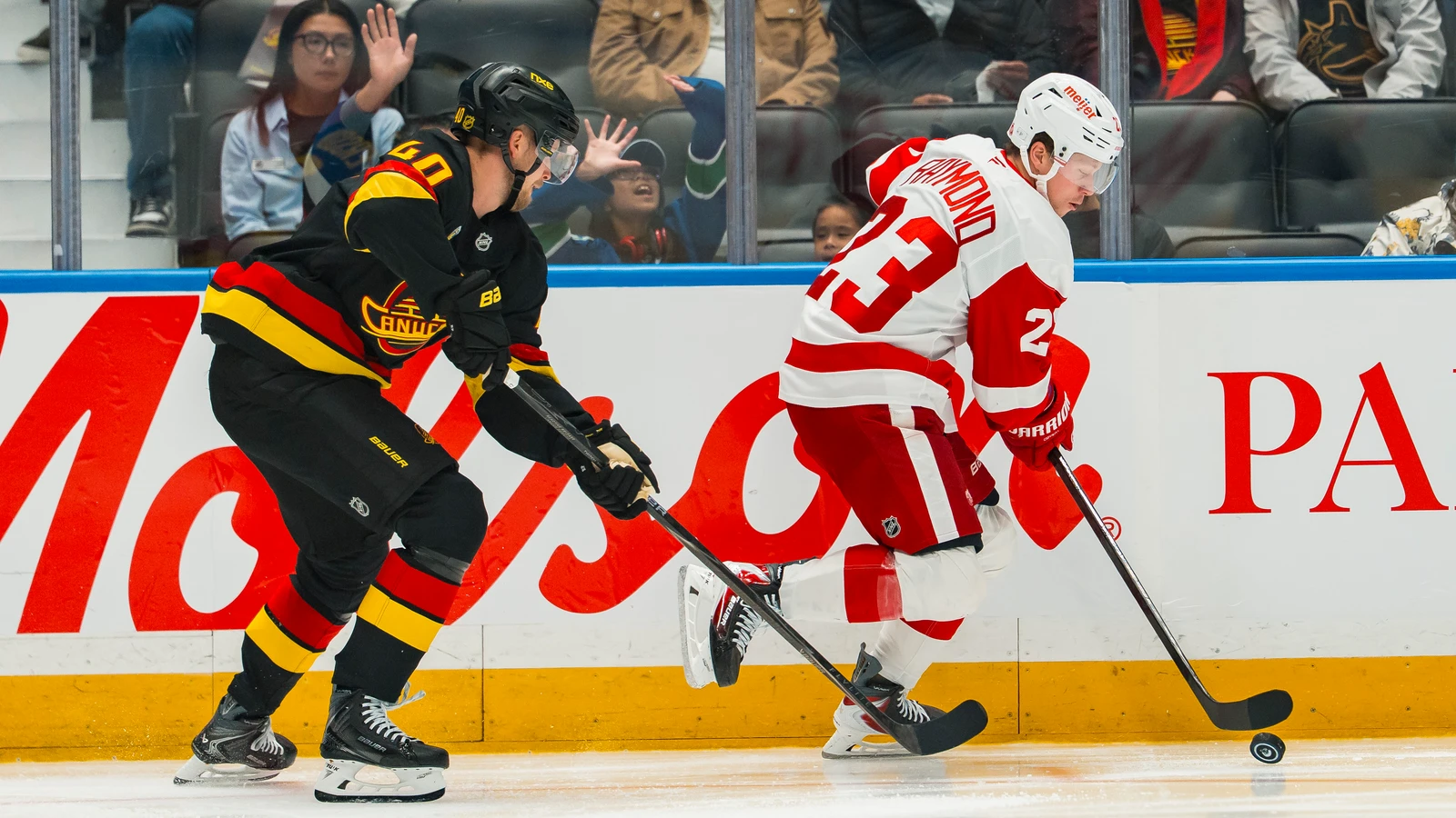 Detroit Red Wings forward Lucas Raymond controls the puck as Vancouver Canucks forward Elias Pettersson reaches with his stick at Rogers Arena.