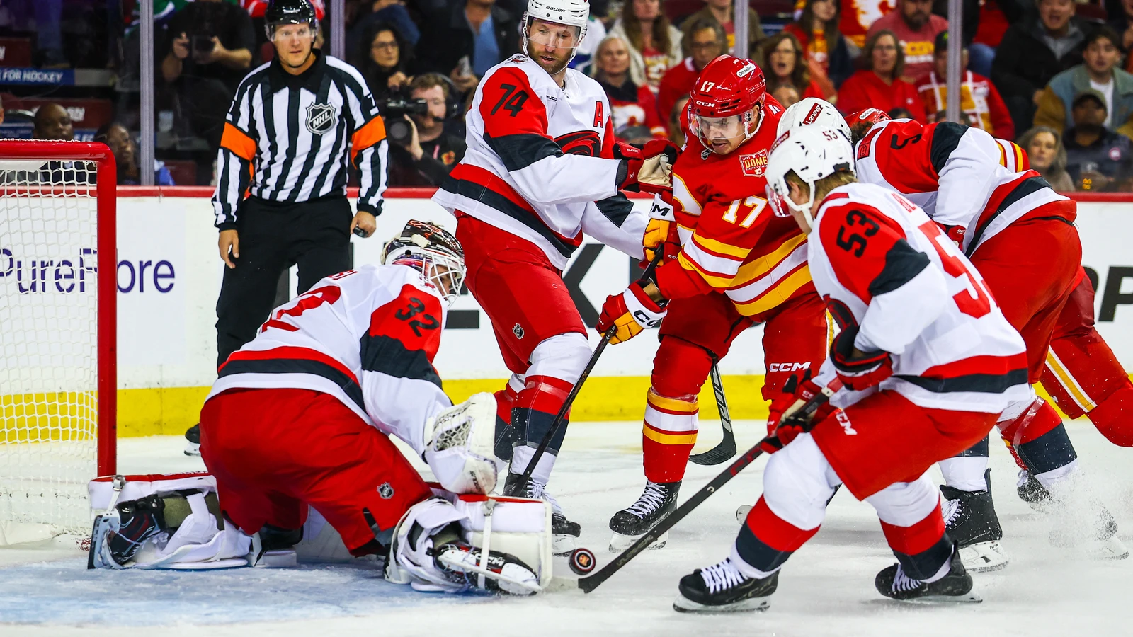 Yegor Sharangovich of the Calgary Flames battles for the puck in front of Carolina Hurricanes goaltender Brandon Bussi at Scotiabank Saddledome.